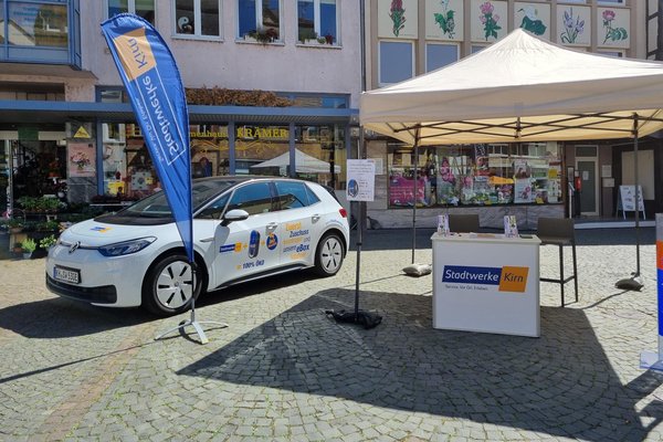 Auf dem Foto sieht man den Messestand der Stadtwerke Kirn GmbH am Kirner Autofrühling 2022. Darauf ist das E-Auto, eine Beachflag und ein Pavillon mit Counter zu sehen.