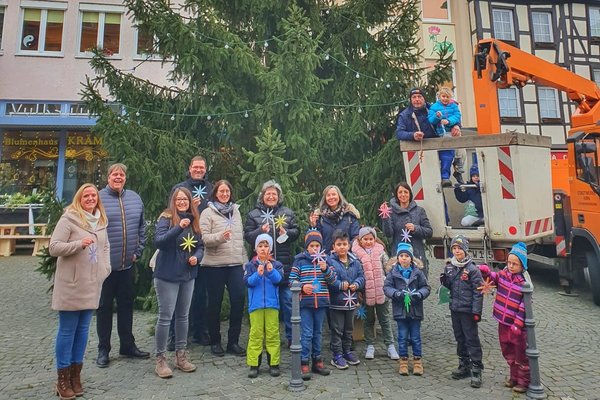 Auf dem Foto sieht man einen Weihnachtsbaum/Tannenbaum der geschmückt wird von Kindergarten-Kindern. Der Bürgermeister ist auch darauf und zwei Stadtwerke Mitarbeiter, Lisa Schneider und Jörg Schallmo.